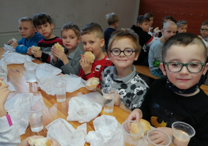 Dzieci siedzą przy stoliku i jedzą posiłek przed odjazdem do Łodzi